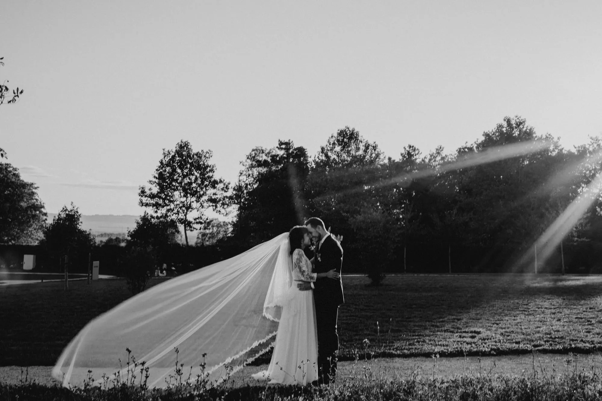 Mariés à contre-jour, voile emporté par le vent, en noir et blanc