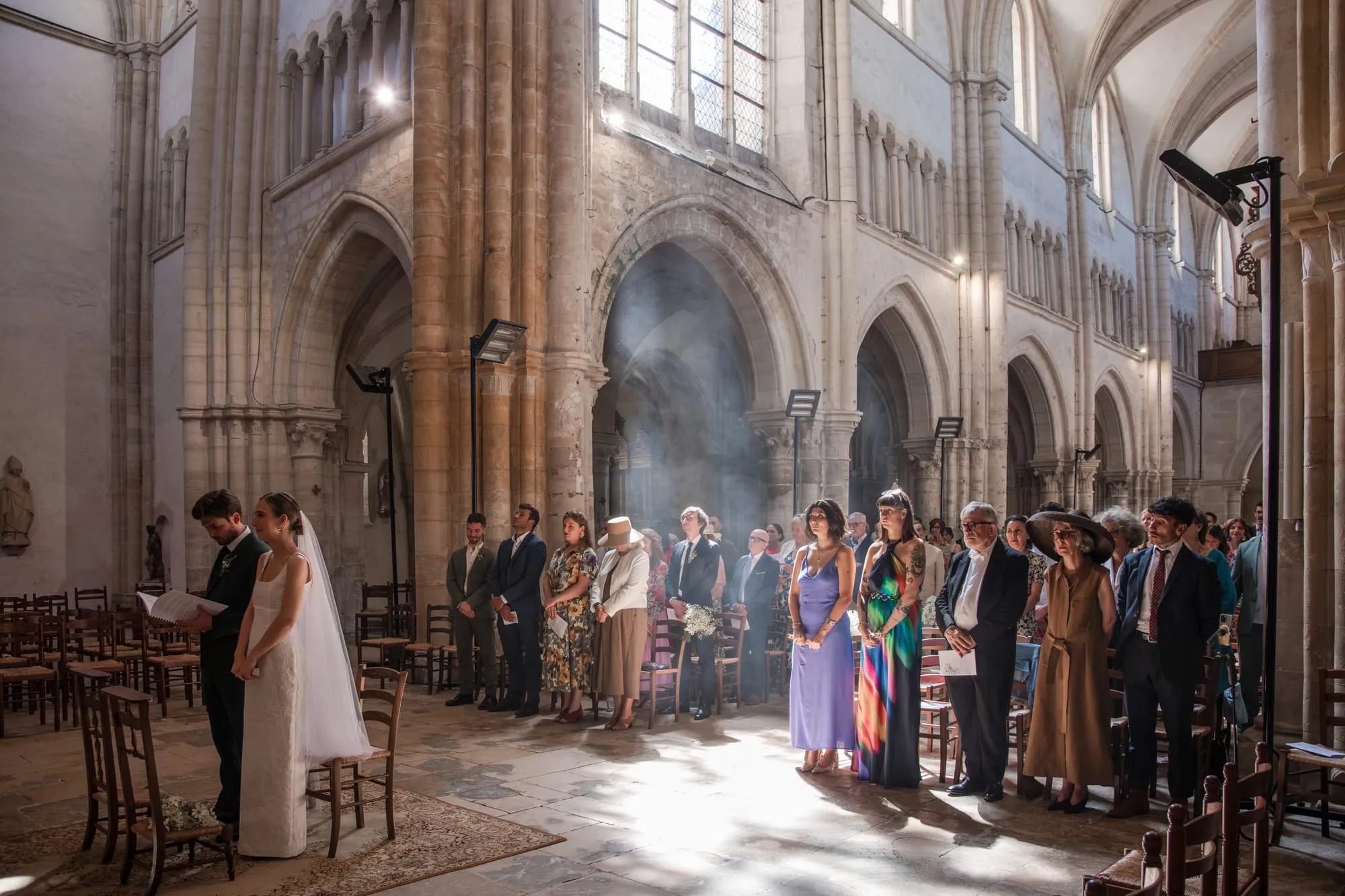 Mariés au pied de l'autel d'une grande église, entourés de leurs invités