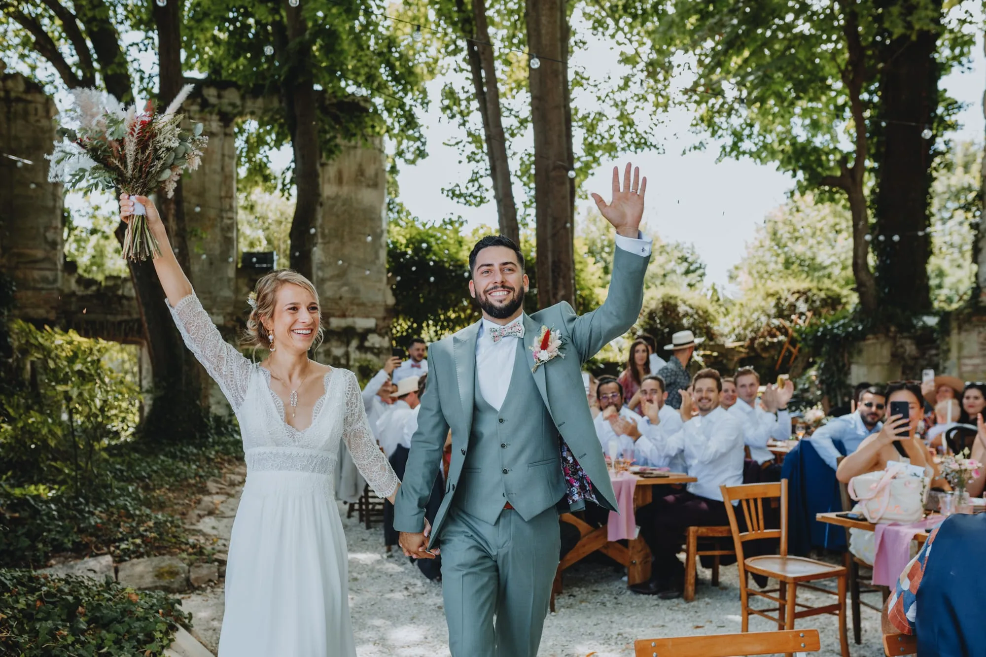 Entrée des mariés, bras levés, sous les applaudissements des invités attablés