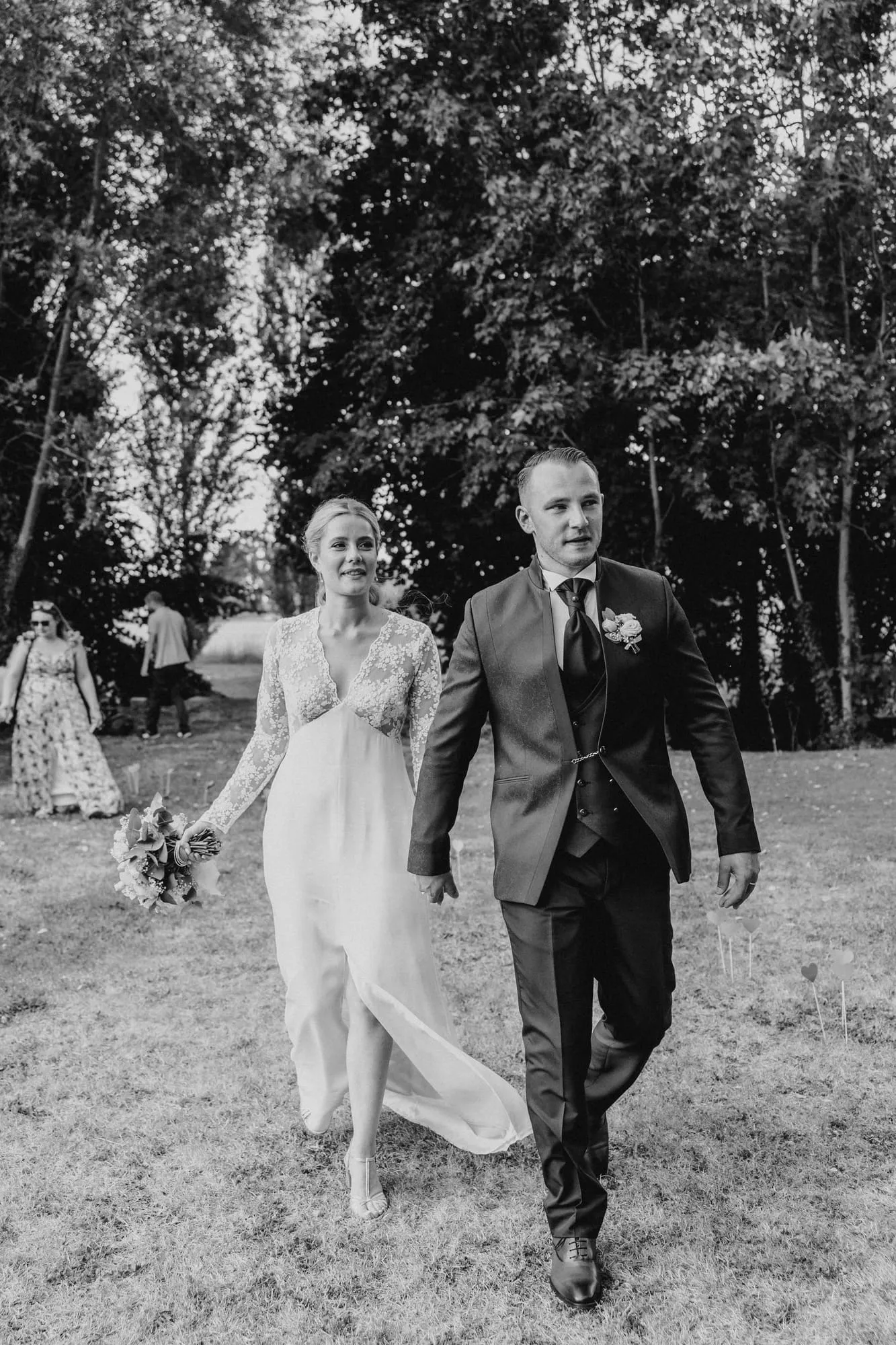 Mariés marchant côte à côte dans un jardin, en noir et blanc