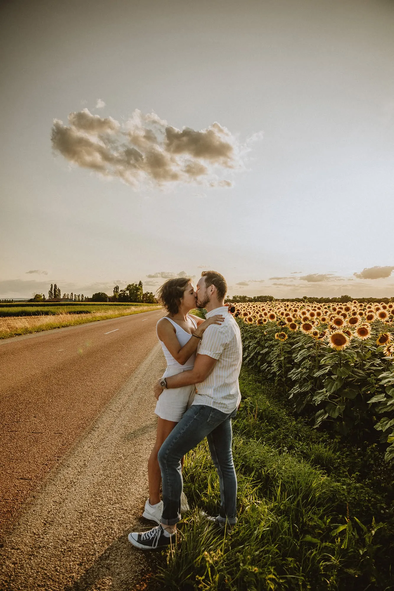 Couple s'embrassant devant un champ de tournesols, avant le mariage