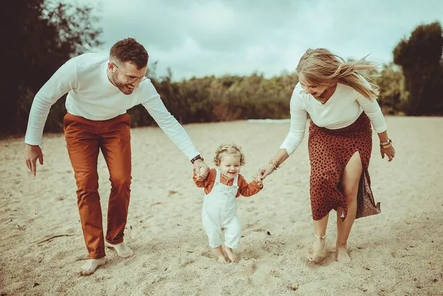 Famille marchant main dans la main sur la plage avec leur petite fille