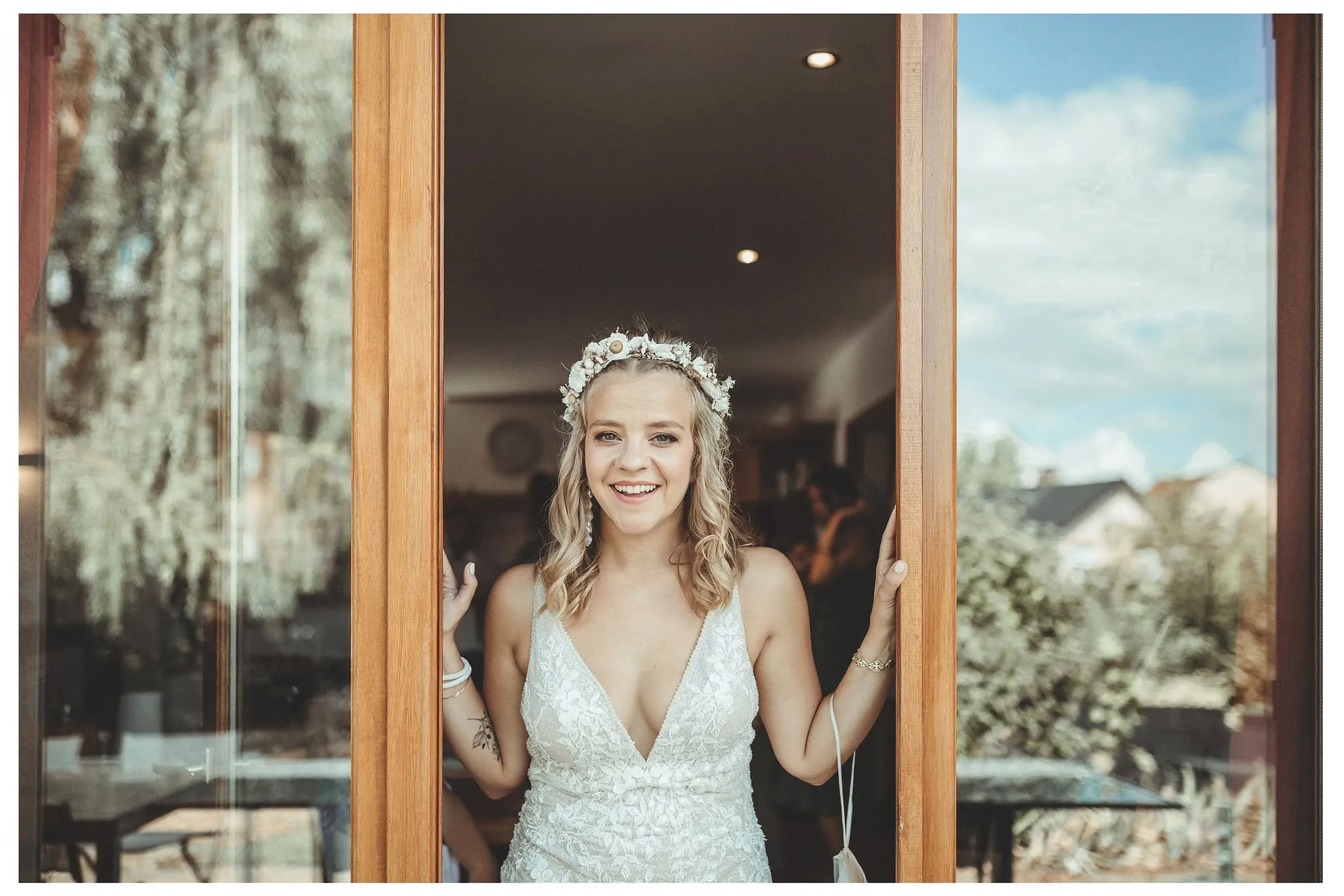 Mariée riant, encadrée dans une porte avant le mariage