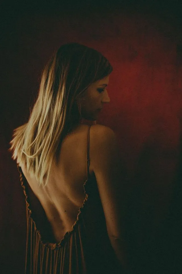 Portrait de femme de dos, robe dos nu, fond rouge