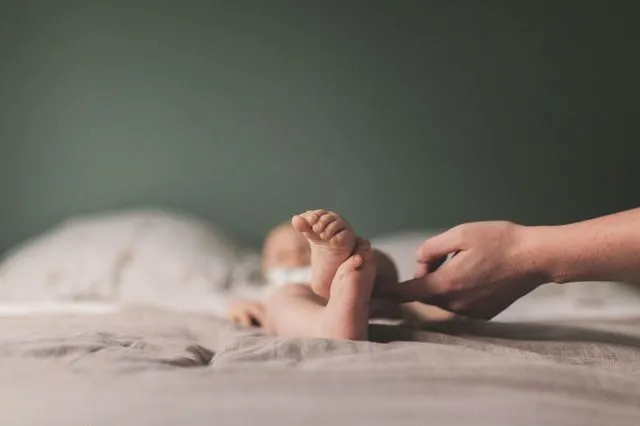 Gros plan sur les petits pieds d'un nouveau-né tenus par une main