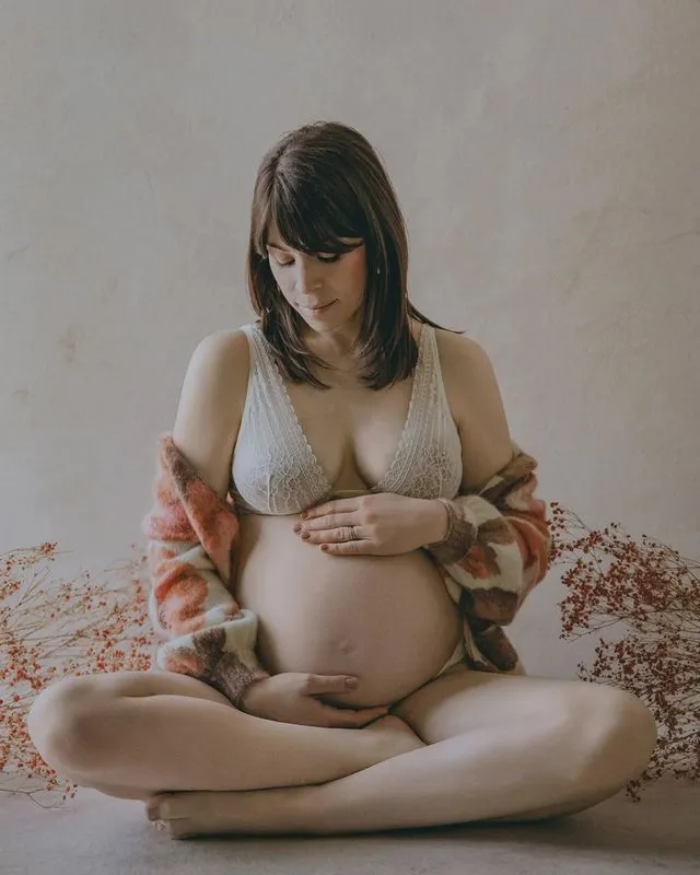 Portrait de femme enceinte assise, fleurs séchées à ses côtés