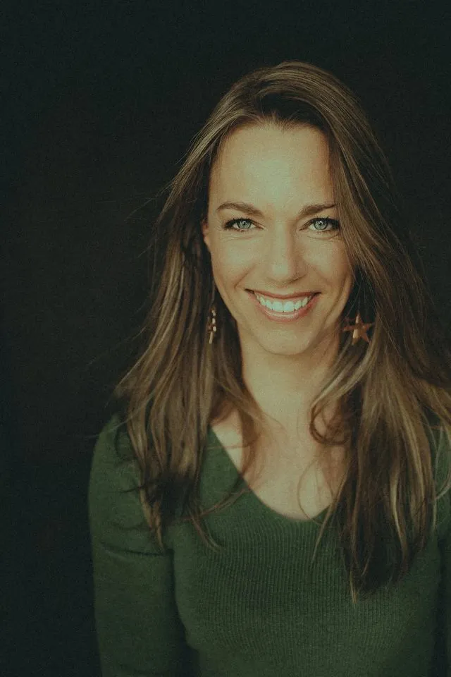 Portrait de femme souriante aux cheveux bruns, fond sombre