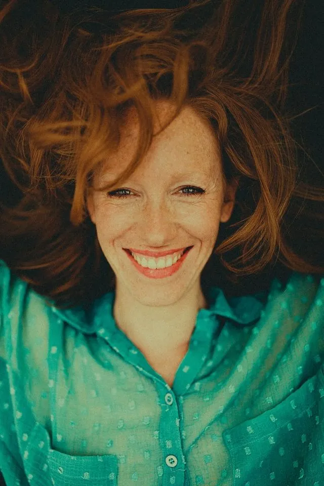 Portrait de femme allongée, cheveux au vent, sourire