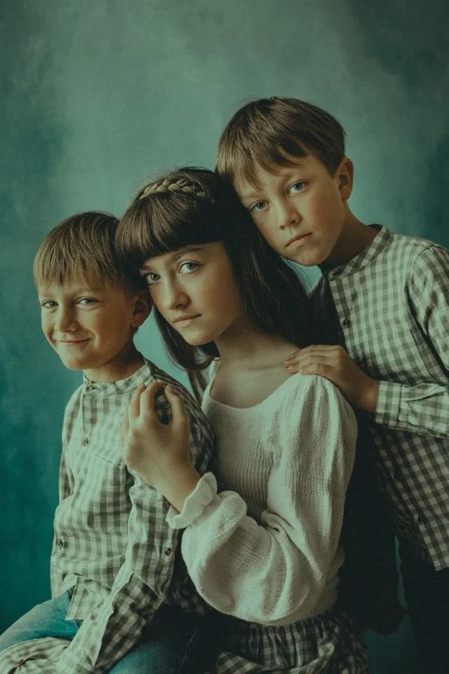 Portrait de fratrie, trois enfants, fond bleu-vert