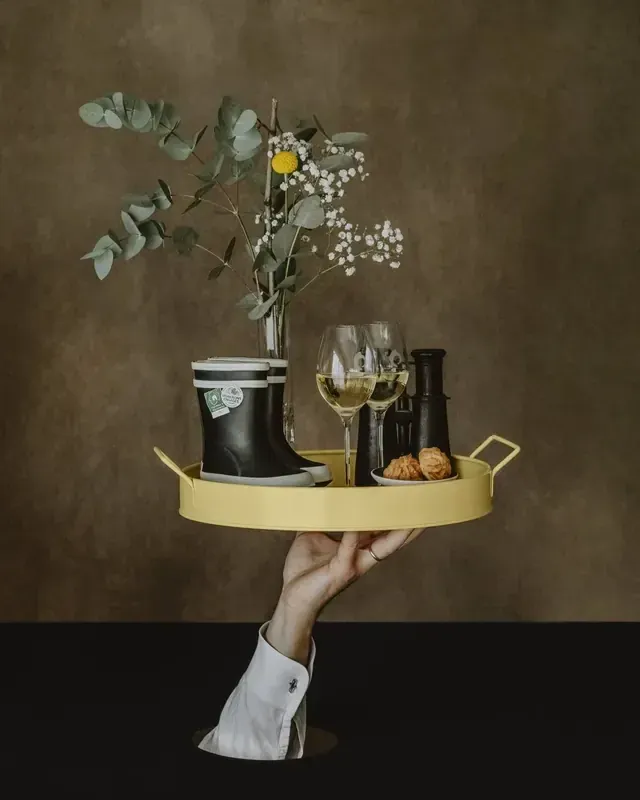 Nature morte : plateau jaune avec petites bottes, verres de vin et jumelles